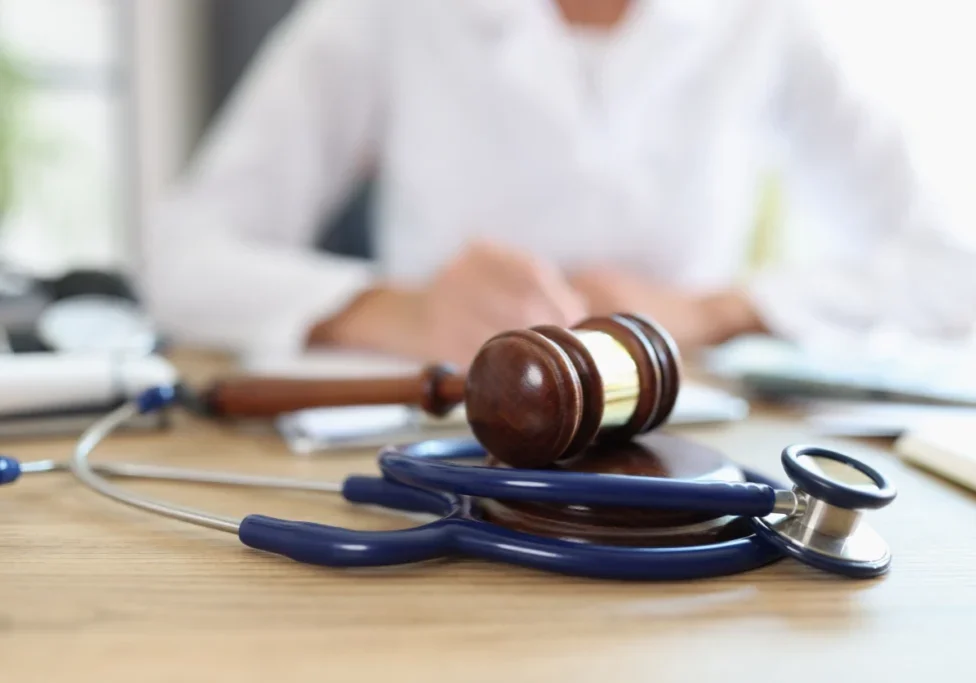 Stethoscope and gavel on wooden table.